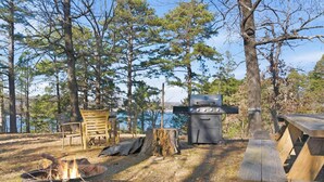 A campsite with a fire pit, a grill, and picnic tables. - Little House on Hickory (Lowell)