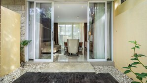 A modern interior with a sliding glass door leading to a living area with a sofa and chairs. - Bhiseka Villa Nusa Dua by Aishwarya Bali (Nusa Dua)
