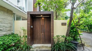 A modern entrance with a wooden door, a nameplate, and a brick wall. - Bhiseka Villa Nusa Dua by Aishwarya Bali (Nusa Dua)