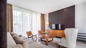 A modern living room with a sofa, chairs, a coffee table, a TV, and a wooden cabinet. - Bhiseka Villa Nusa Dua by Aishwarya Bali (Nusa Dua)