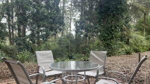Una mesa redonda con cuatro sillas en un jardín.