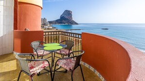 A balcony with a table and chairs, a view of the sea, and a distinctive rock formation in the distance. - Inftour Oceanic 6 Apartamento (Calp)