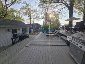 Una terraza con sillones de descanso, una parrilla y vistas a casas y árboles.