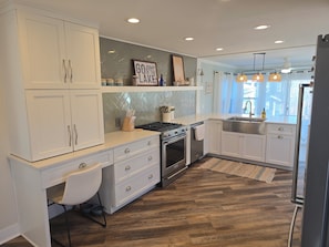 A modern kitchen with white cabinetry, a built-in oven, a stainless steel sink, and a herringbone-patterned backsplash.