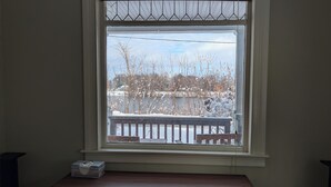 Ein Fenster mit Blick auf eine verschneite Landschaft, eine hölzerne Bank und ein kleiner Tisch mit Taschentuchbox.