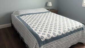 Ein Schlafzimmer mit einem Bett, einem Nachttisch, einer Lampe und einem gerahmten Bild an der Wand.
