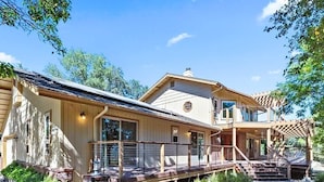 Ett tvåvåningshus med en inglasad veranda, ett stort fönster och en stensatt gångväg som leder till entrén.