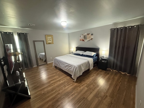 A bedroom with a bed, bedside tables, a mirror, and a wall decoration.