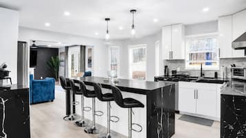 A modern kitchen with a central island, bar stools, and white cabinetry.