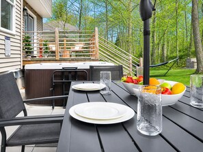 An outdoor patio with a hot tub, dining table, chairs, and a fruit bowl. - LUXE HAUS· Sleeps 12· Private Spa · 2 Game Rooms w Arcade & Theater · Playground (Tobyhanna)