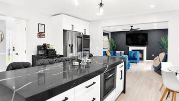 A modern kitchen with a marble island, built-in appliances, and a dining area with a white table and chairs.