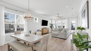 Un salon moderne comprenant un coin repas, un canapé, un téléviseur et un ventilateur de plafond.