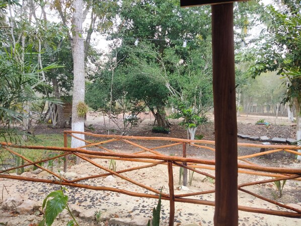 A wooden structure with a grid of beams, surrounded by trees and a dirt ground.