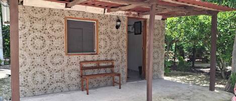 A covered outdoor area with a bench, a door, and a window.