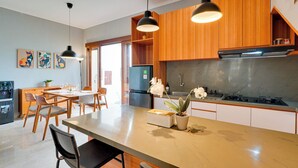 Une cuisine moderne avec des meubles en bois, un plan de travail en marbre et des luminaires suspendus.