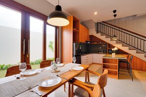 Eine moderne Küche mit Holzausbau, ein Essbereich mit Holztisch und Stühlen sowie eine Treppe, die in einen oberen Bereich führt.