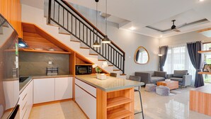 Une cuisine moderne dotée d’un îlot central en bois, d’appareils électroménagers intégrés et d’un escalier menant à un niveau supérieur.