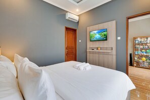 Ein Hotelzimmer mit Bett, einem an der Wand montierten Fernseher und einer Holztür.