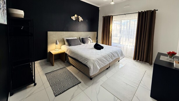 A modern bedroom with a large bed, bedside tables, a desk, and a window with curtains. - Rihla Residences - Civic Road

Fabulous 4-bedroom house in Cape Town (Cape Town)