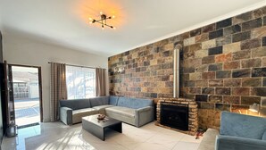 A modern living room with a stone fireplace, a sectional sofa, and a coffee table. - Rihla Residences - Civic Road

Fabulous 4-bedroom house in Cape Town (Cape Town)