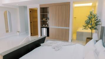 Ein modernes Hotelzimmer mit einem großen Bett, einem begehbaren Kleiderschrank, einem Badezimmer und einem kleinen Balkon.