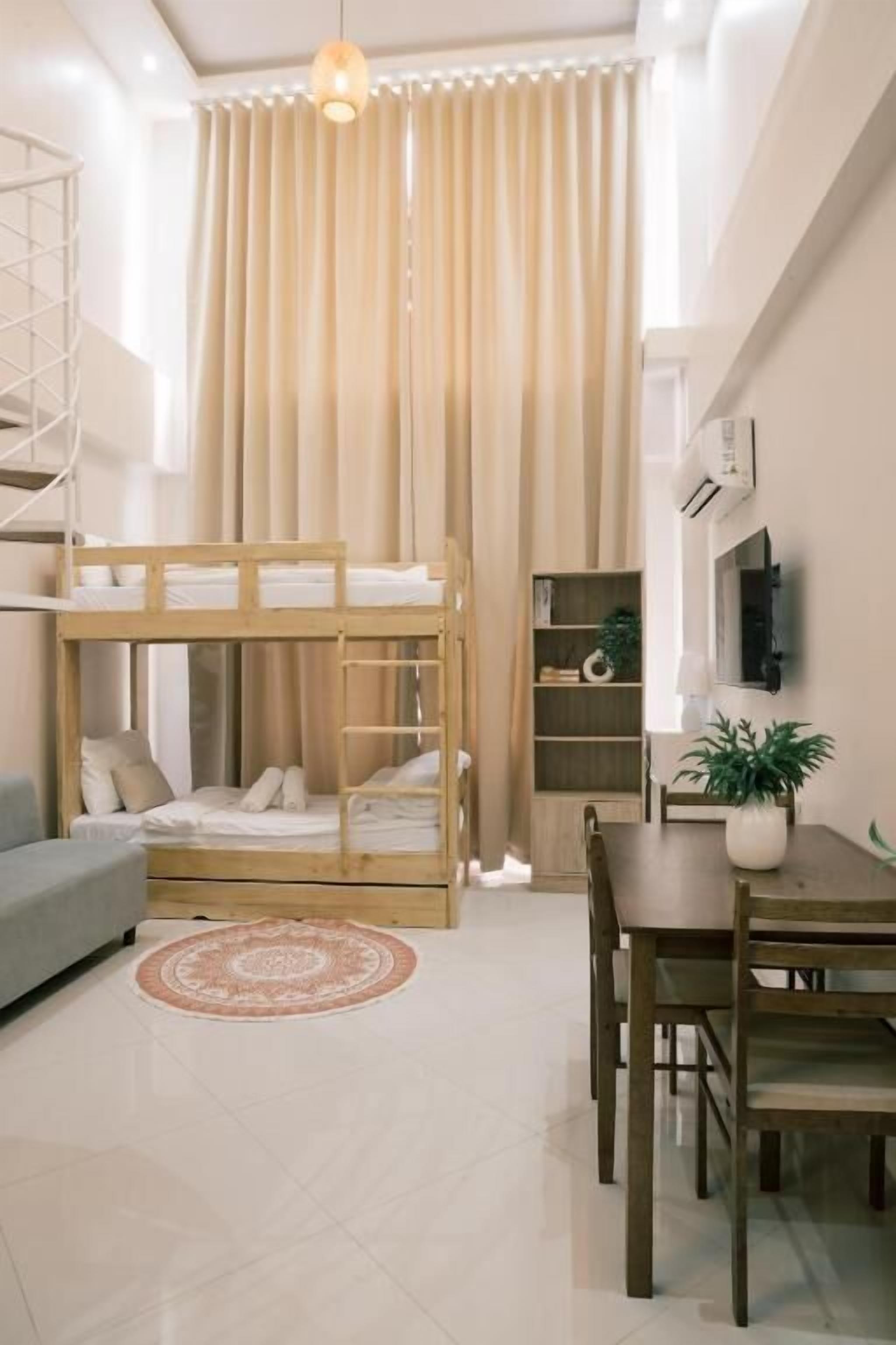 A compact living space with bunk beds, a dining area, and a TV mounted on the wall.