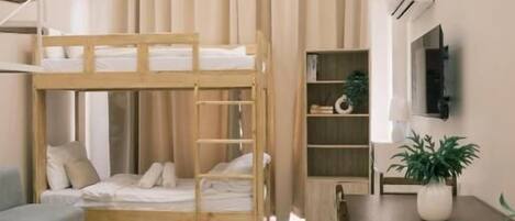 A compact living space with bunk beds, a dining area, and a TV mounted on the wall.