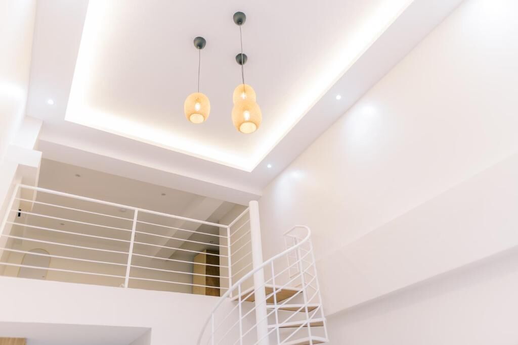 Un interior moderno con una escalera espiral blanca y un entrepiso con barandilla.