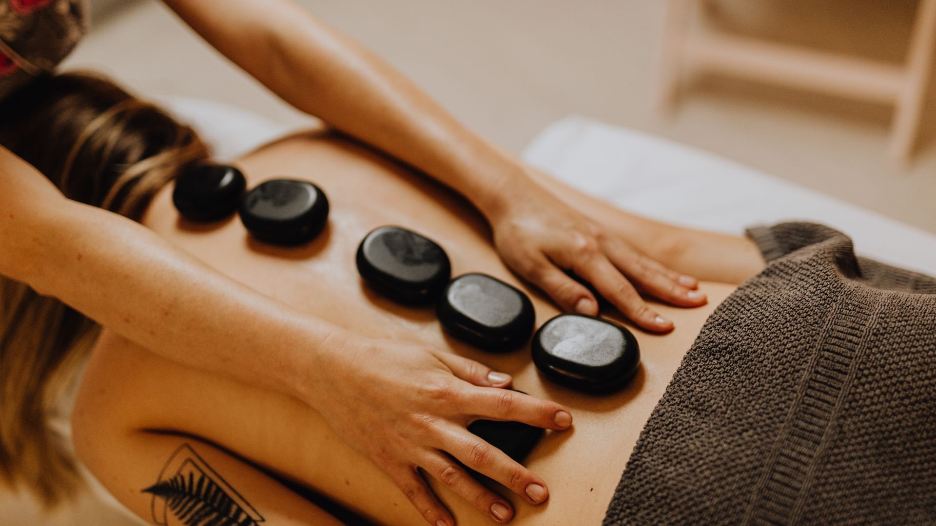 A massage therapy session with a person lying face down on a massage table, receiving pressure from a therapist's hands and feet.