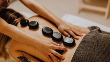 A massage therapy session with a person lying face down on a massage table, receiving pressure from a therapist's hands and feet.