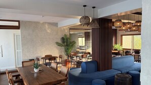 Un intérieur moderne avec une table à manger en bois, des canapés bleus, des chaises en osier et des lampes suspendues en osier.