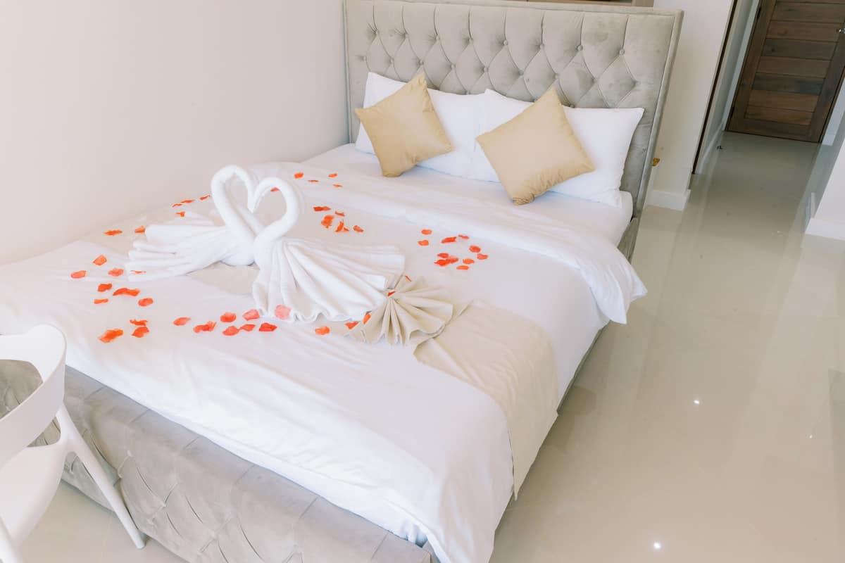 A neatly made bed with a white duvet, two beige pillows, and a decorative towel arrangement.