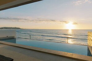 An infinity pool with a view of the ocean and sunset. - Palms La Union Suites (San Juan)
