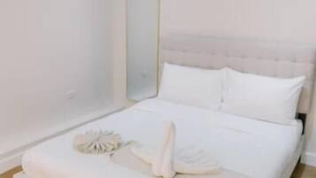 A bedroom with a large bed, a mirror, and a wooden floor.