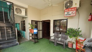 A room with a green carpet, a ceiling fan, a no-smoking sign, and potted plants. - Dream Homestay (Ujjain)