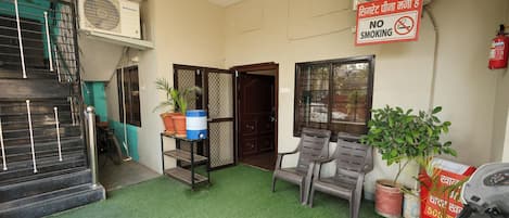A room with a green carpet, a ceiling fan, a no-smoking sign, and potted plants.