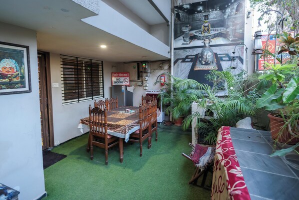 A dining area with a table and chairs, a 'No Smoking' sign, and potted plants. - Dream Homestay (Ujjain)