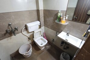 A bathroom with a toilet, bidet, sink, and a mirror. - Dream Homestay (Ujjain)