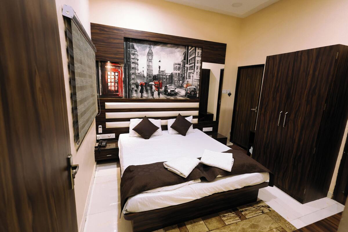 Une chambre avec un grand lit, une armoire et un tableau représentant un paysage urbain accroché au mur.