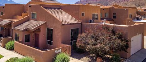 A residential building with a flat roof, multiple windows, and a visible garage door.