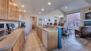 A spacious kitchen with wooden cabinets, a central island, and a dining area with a blue accent wall. - Easy, comfortable stay near Moab's best adventures (Moab)