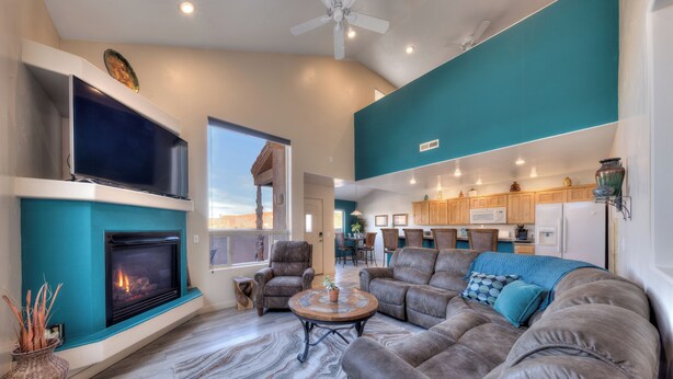 A modern living room with a fireplace, comfortable seating, and a kitchen area in the background. - Easy, comfortable stay near Moab's best adventures (Moab)