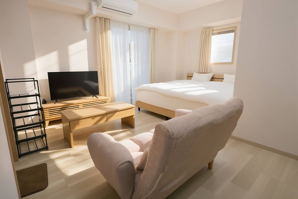 A hotel room with a bed, a TV, a desk, and a chair.