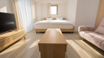 A modern hotel room with a bed, a TV, a wooden coffee table, and a sofa.