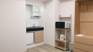 A compact kitchenette with a microwave, kettle, and a small refrigerator. - SDC Namba (Osaka)