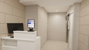A reception desk with a computer monitor, a wall-mounted screen, and a tiled floor. - SDC Namba (Osaka)
