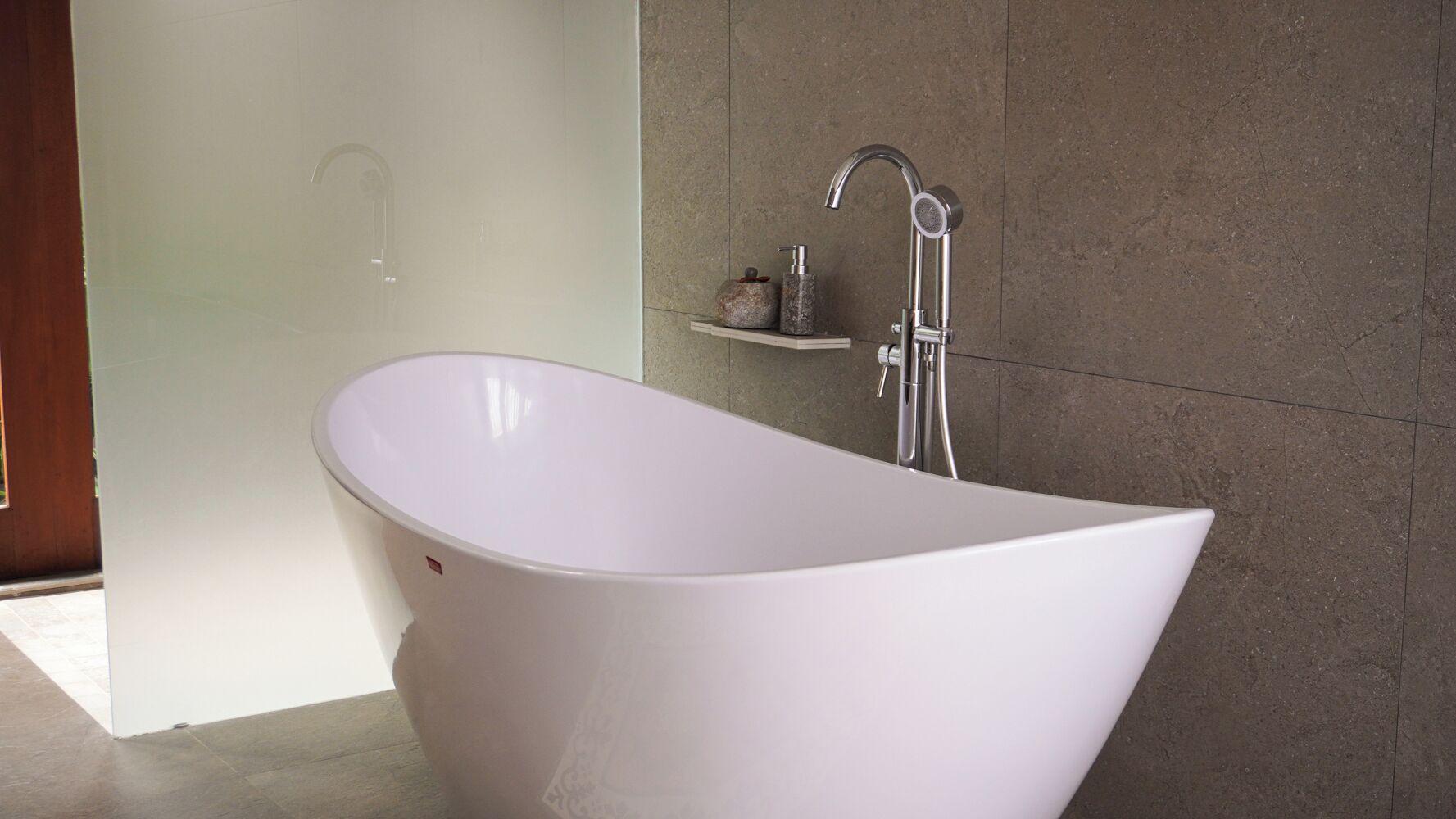 Une baignoire sur pied dans une salle de bain moderne, avec un mur en pierre et une petite étagère contenant des articles de toilette.