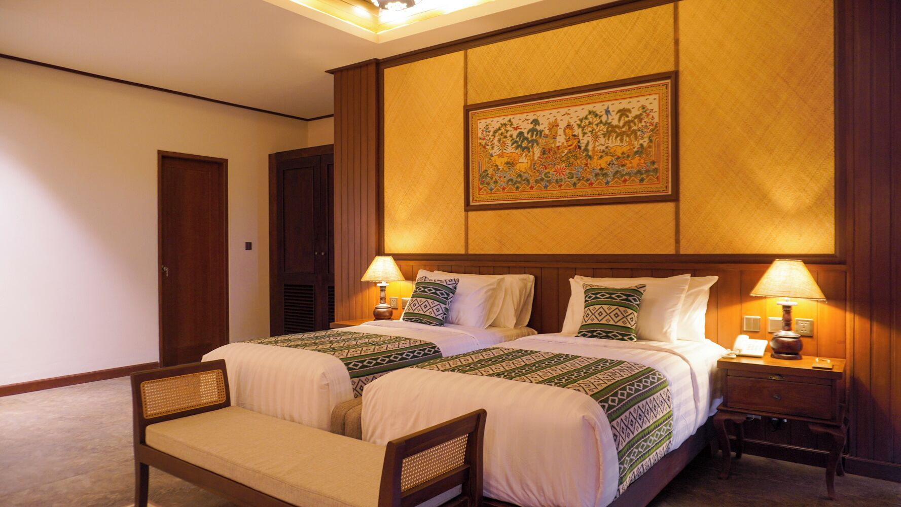 A hotel room with two beds, a wooden headboard, a large painting above the beds, and bedside lamps.