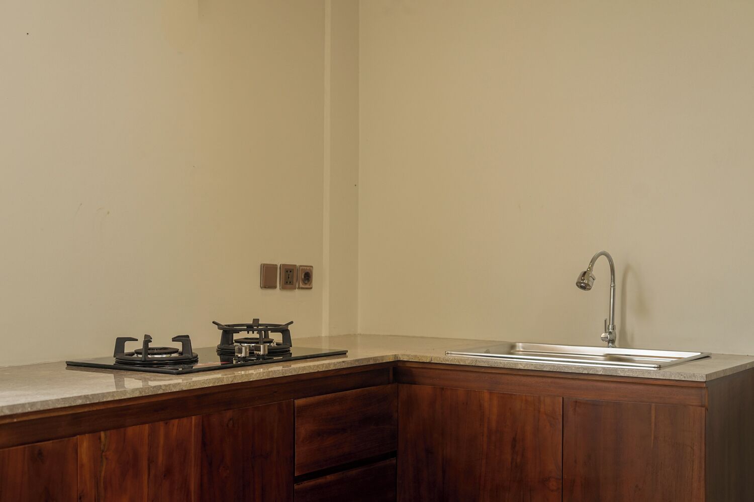 Una cocina con estufa a gas, lavamanos y armarios de madera.