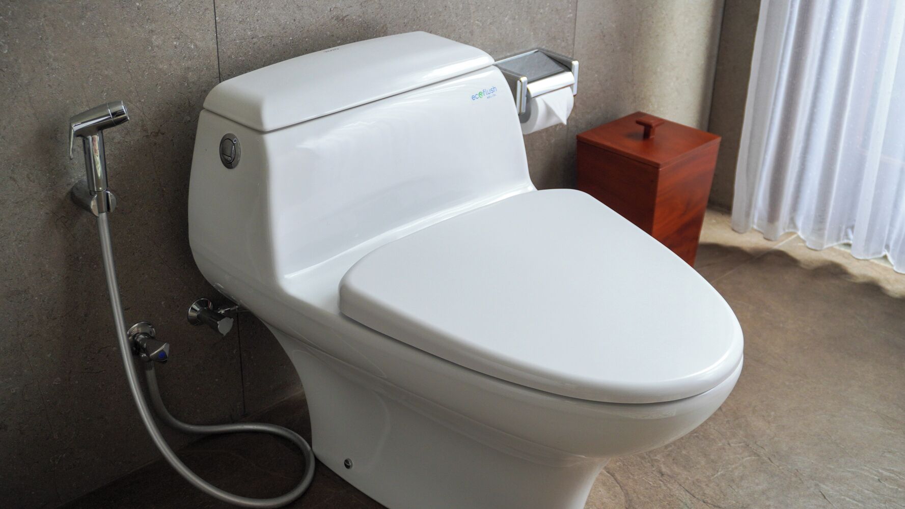 Des toilettes modernes dotées d’un bouton de chasse d’eau et d’un accessoire de type bidet.
